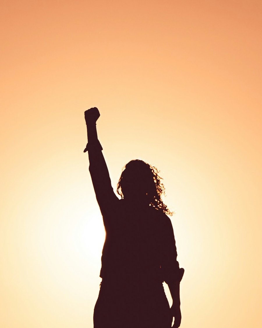 Silhouette, poing levé face au soleil levant, symbole de vitalité